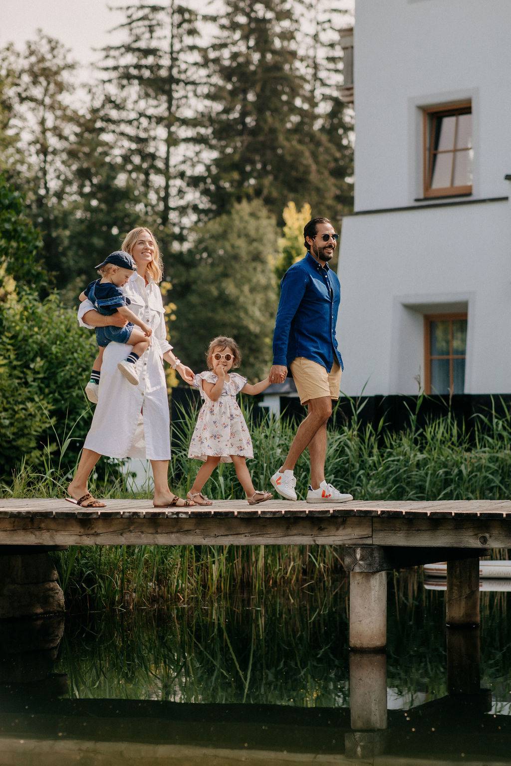 Family crosses the footbridge at the swimming lake in the Naturhotel Forsthofgut