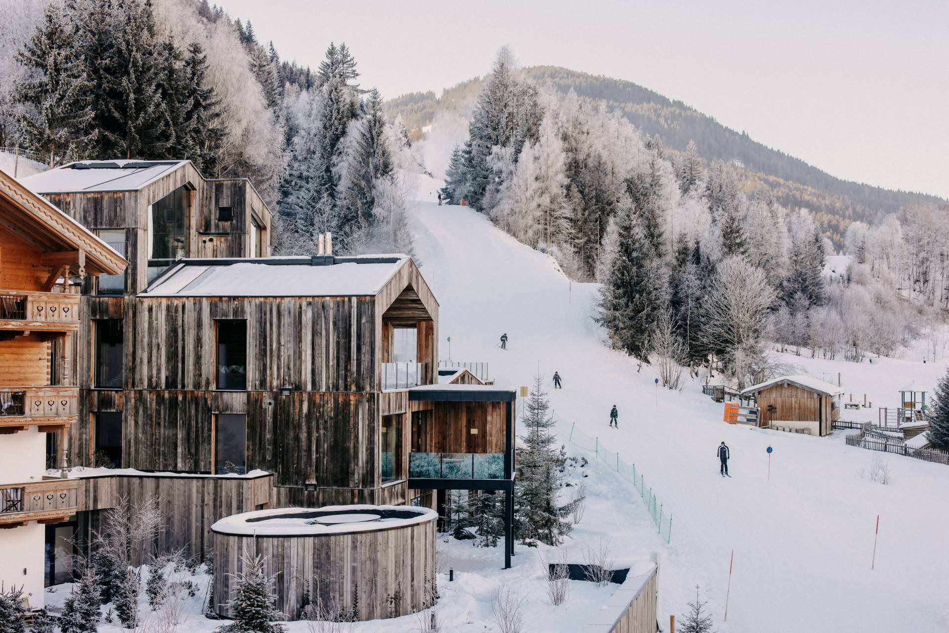 Außenansicht Naturhotel Forsthofgut im Winter mit Skifahrern