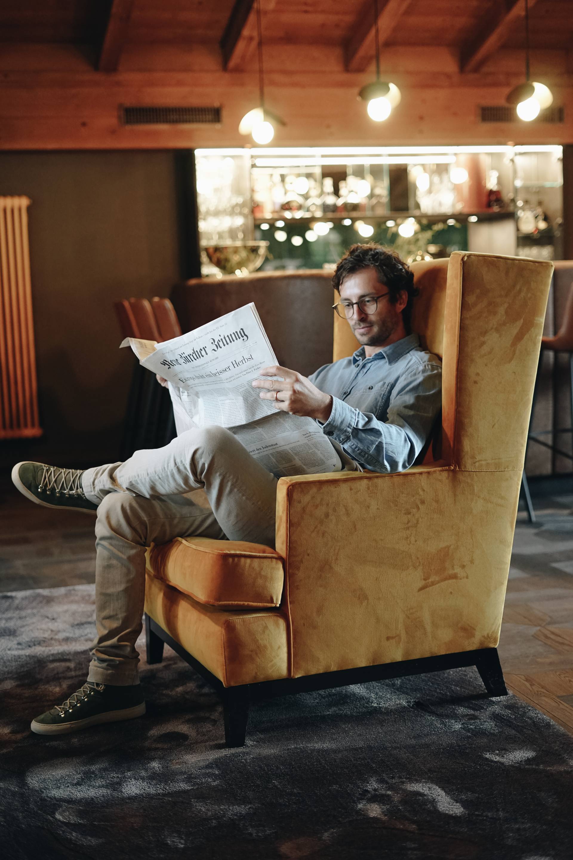 Mann liest Zeitung in Sessel Cocktailbar Naturhotel Forsthofgut