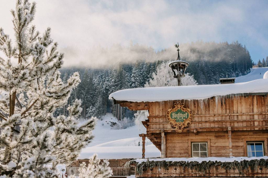 Zwei Frauen entspannen im Seepool des Naturhotel Forsthofgut an einem winterlichen Tag.