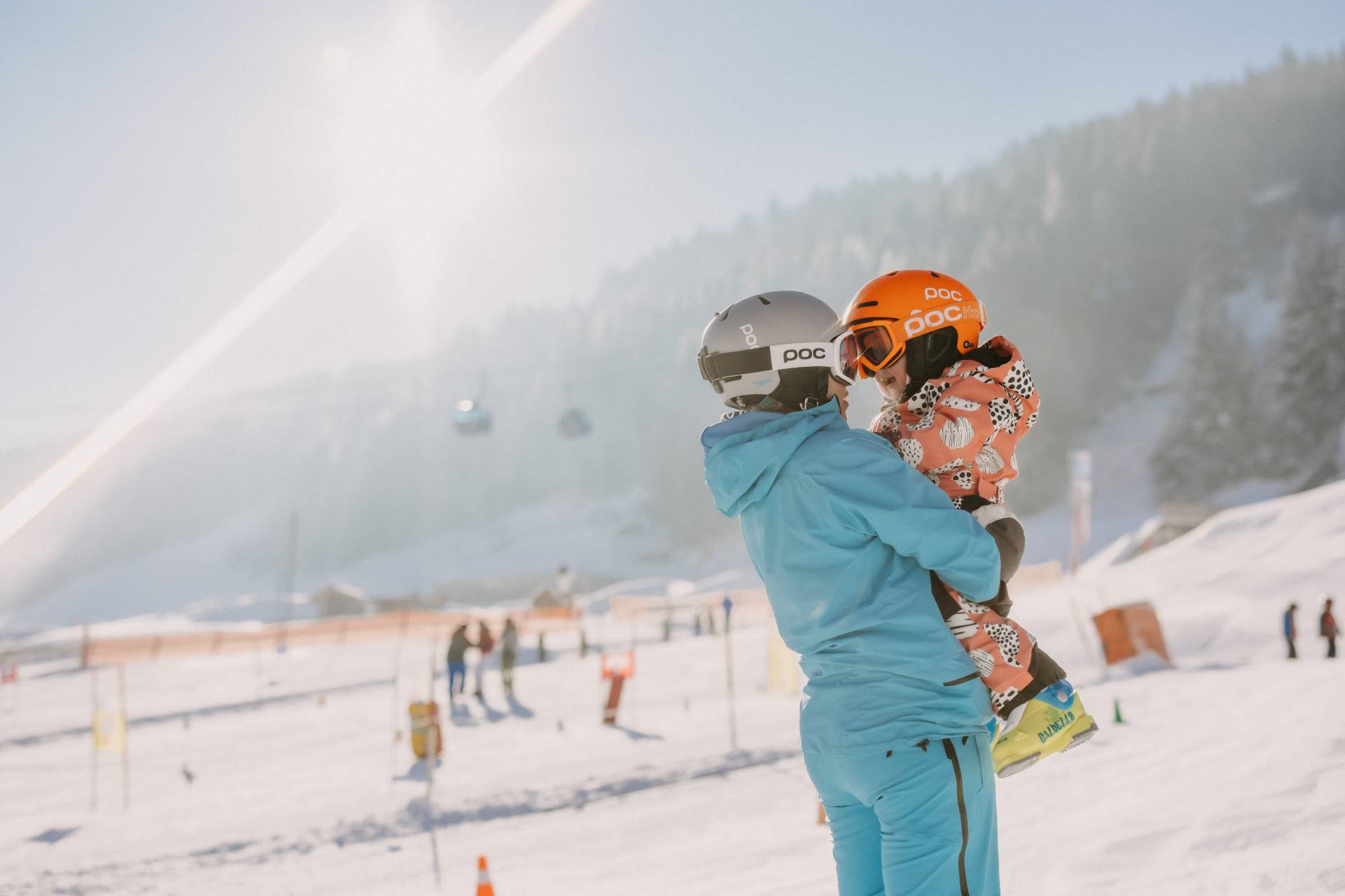 Person hält Kind auf den Armen im Skigebiet