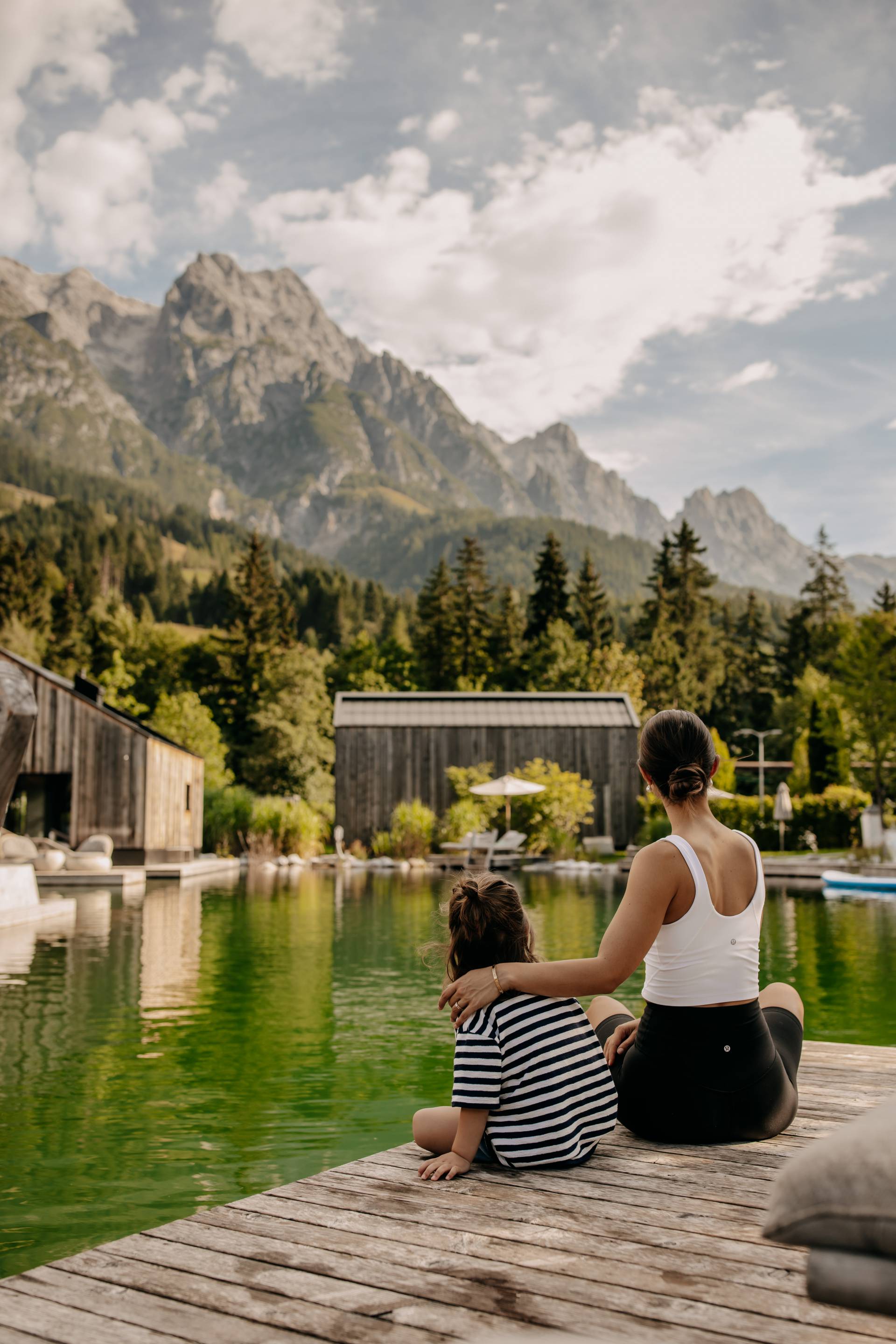 Mother and child sitting on the jetty and enjoying the view of the Steinberge mountains