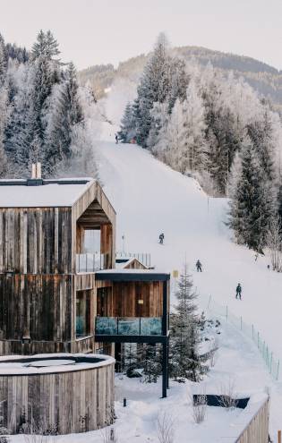 Außenansicht Naturhotel Forsthofgut im Winter mit Skifahrern