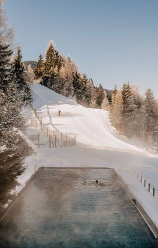 Außenpool mit Blick auf Skipiste im Winter