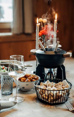 Topf mit Käsefondue, Brot und Kartoffeln im 1617 bei Kerzenschein. 