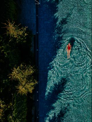 Frau schwimmt im Infinity Pool des Naturhotel Forsthofgut