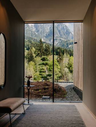 Woman in the 25m sportpool enjoing the view of the Leoganger Steinberge / Naturthotel Forsthofgut Garden loft suit interior