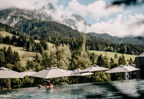 Frau im Infinity Pool mit Blick auf die Leoganger Steinberge