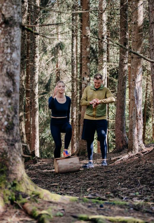 Fitness in Leogang - Personal Trainer mit Frau im Wald machen Sport
