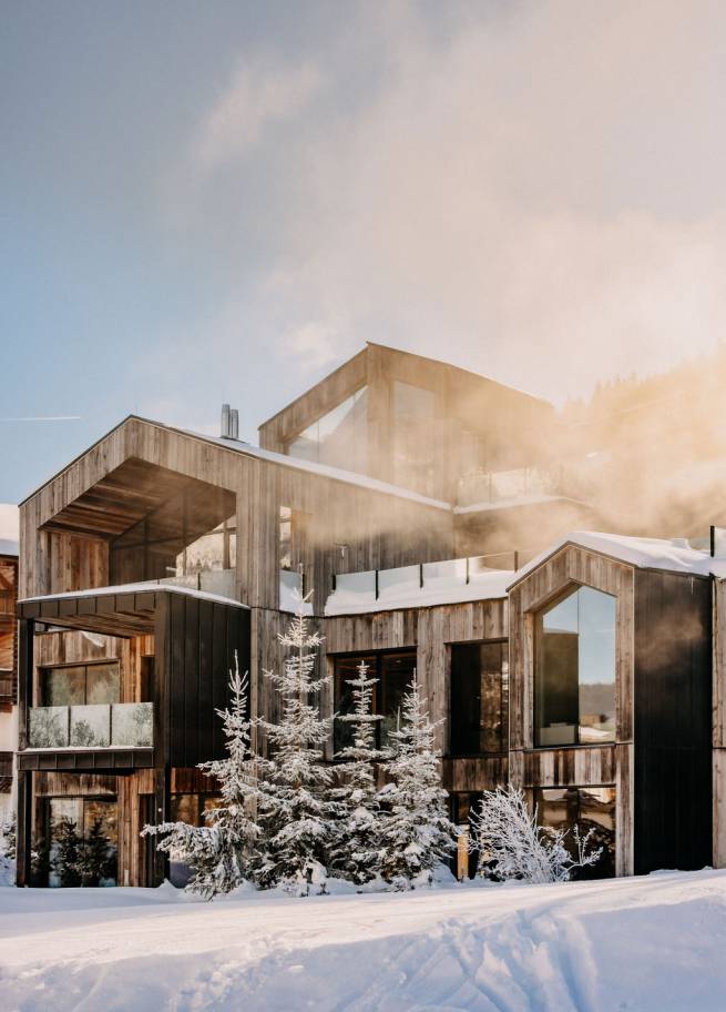 Außenansicht Naturhotel Forsthofgut im Winter mit Skifahrern