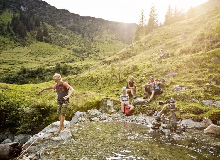 Familie wandert und macht Pause am Bergsee in Österreich Leogang