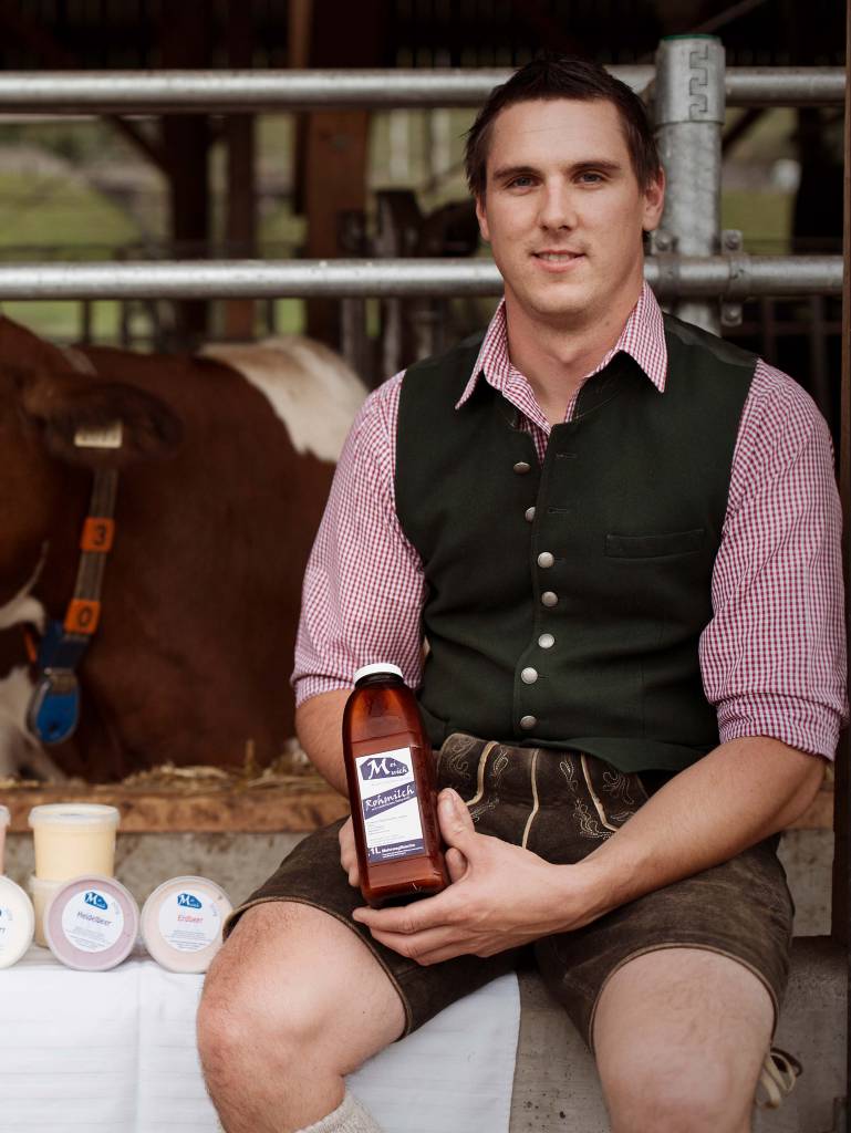 Landwirt mit eigener Milch im Kuhstall in Leogang