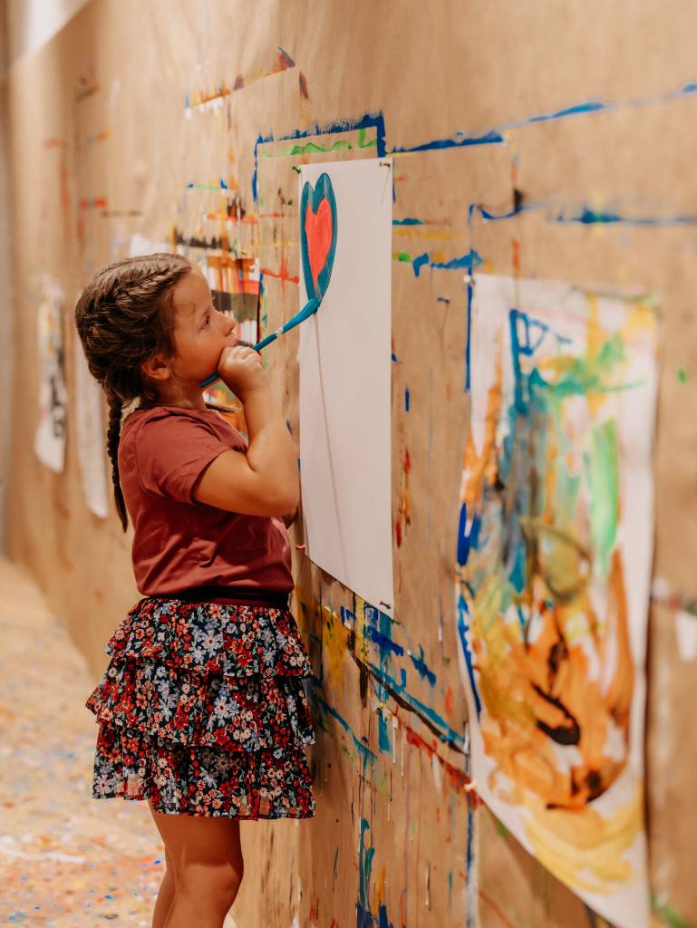 Kind malt Herz auf Papier an der Wand