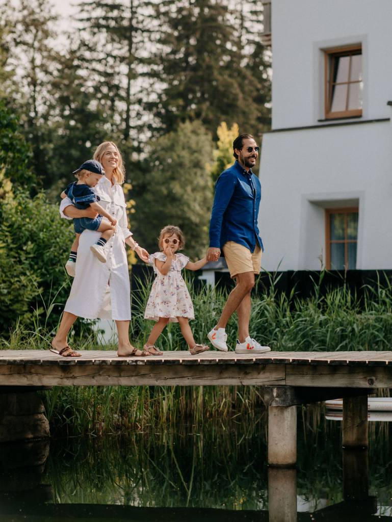Family crosses the footbridge at the swimming lake in the Naturhotel Forsthofgut