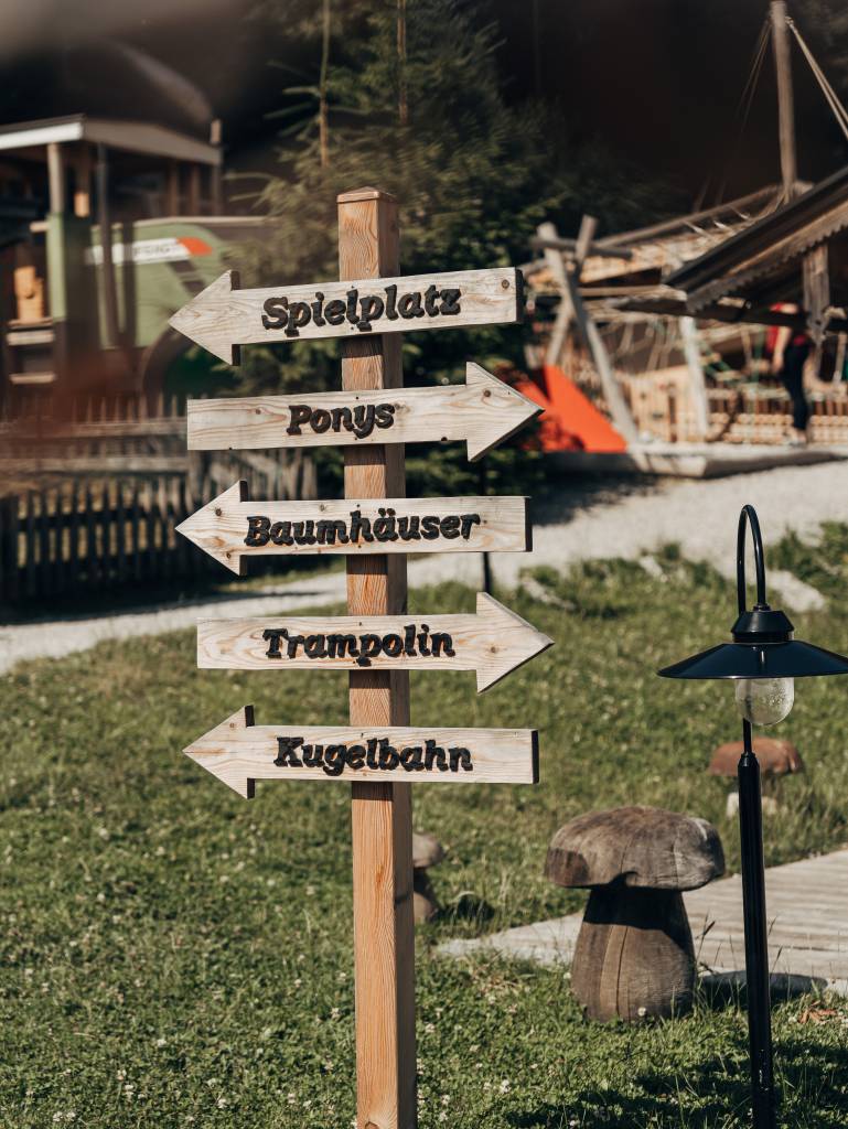 waldspielplatz mit Holzgeräten, Rutschen und einer Murmelbahn im Forsthofgut