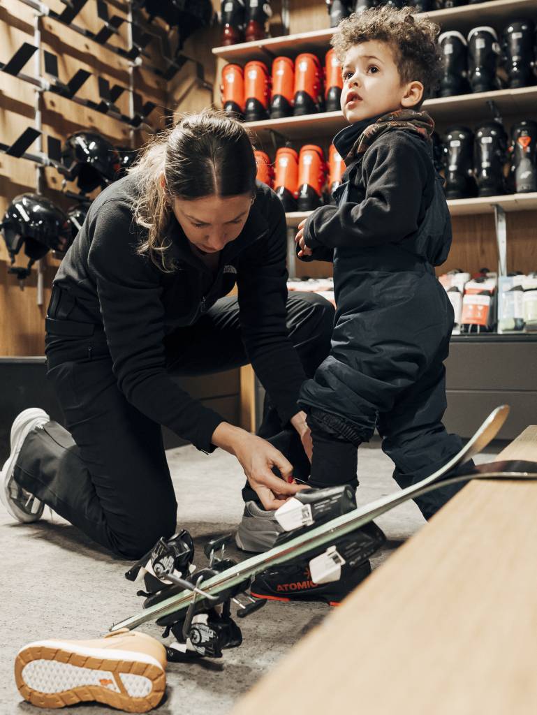 Mutter ist mit ihrem Sohn im Skiverleih des Naturhotel Forsthofguts und probiert Ski und Skischuhe an