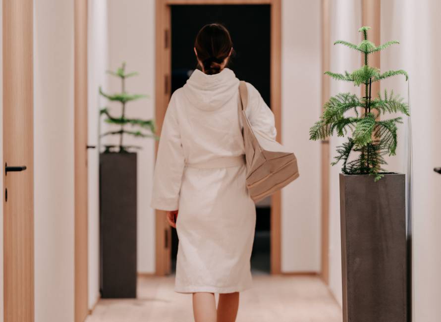 Spa & Wellness im Forsthofgut - Frau in Bademantel geht Flur entlang