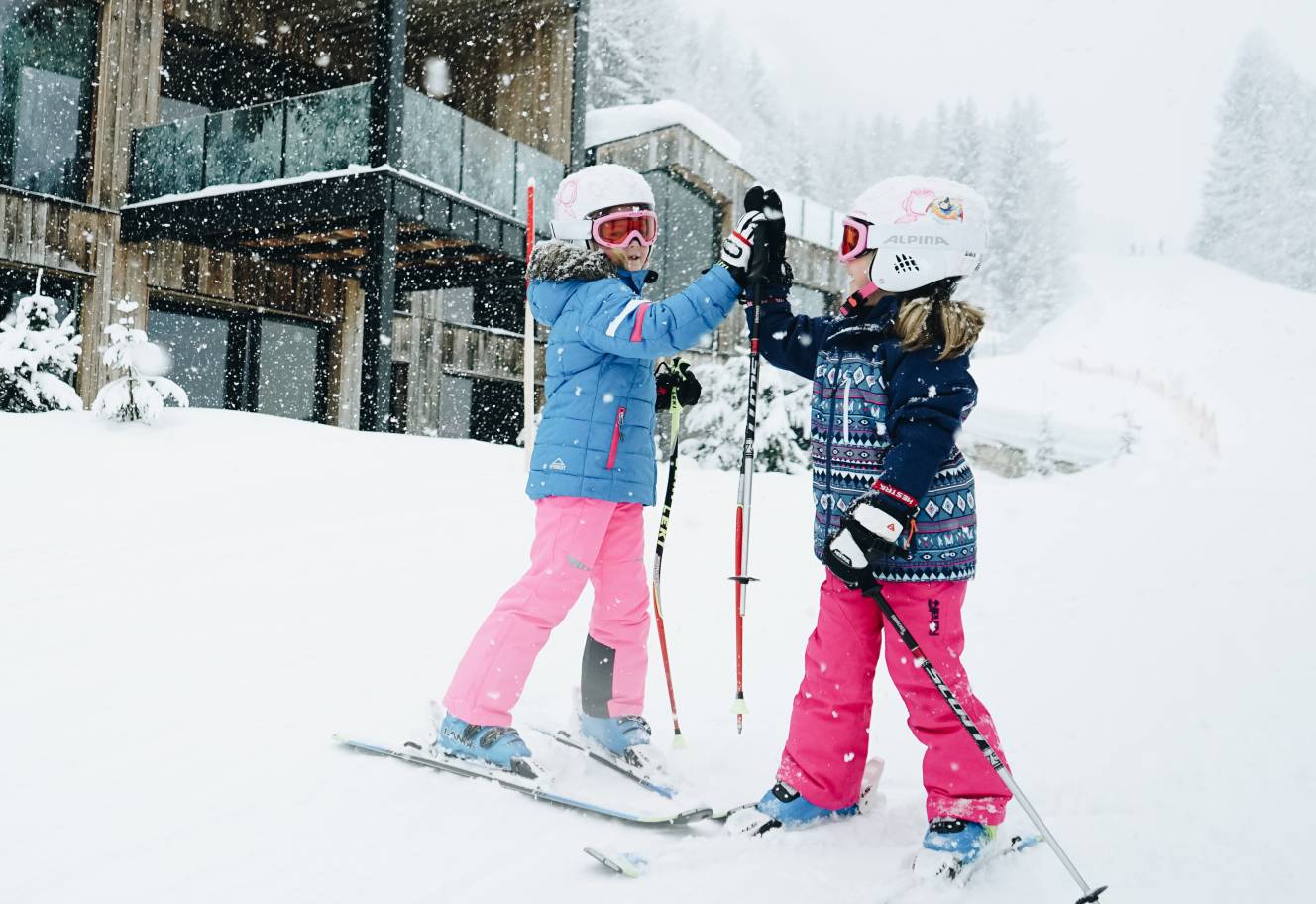 Kinder auf Ski geben sich High Five