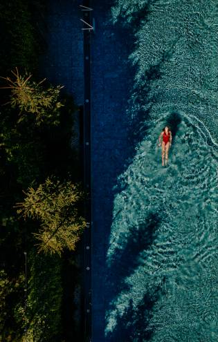 Frau schwimmt im Infinity Pool des Naturhotel Forsthofgut