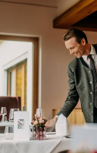 Kellner deckt Tisch im Restaurant des Naturhotel Forsthofgut