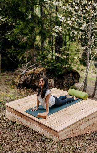 Frau beim Yoga im Wald in Leogang