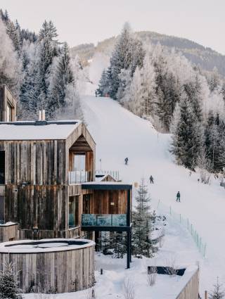 Außenansicht Naturhotel Forsthofgut im Winter mit Skifahrern