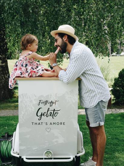 Mann isst mit Tochter ein Eis im Garten des Naturhotel Forsthofgut