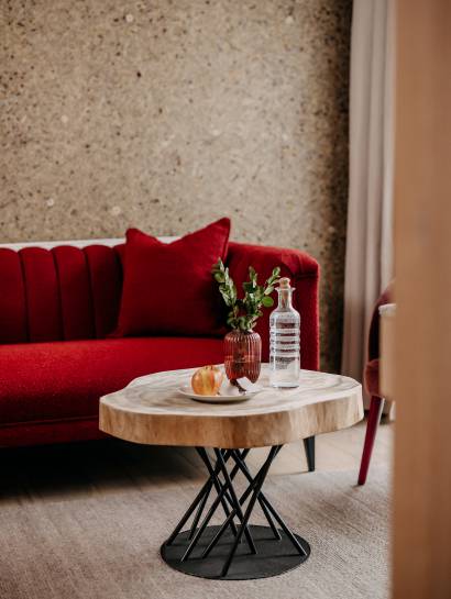 Rote Couch und Holztisch im Zimmer des Naturhotel Forsthofgut
