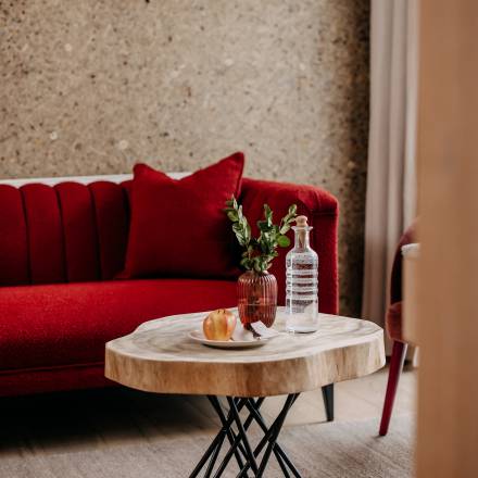 Rote Couch und Holztisch im Zimmer des Naturhotel Forsthofgut