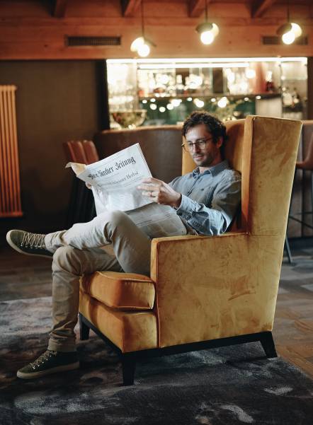 Man reading the newspaper in an armchair Naturhotel Forsthofgut