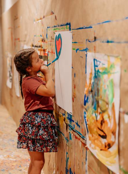 Kind malt Herz auf Papier an der Wand