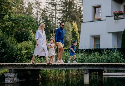 Familie läuft über Steg im Naturhotel Forsthofgut in Österreich