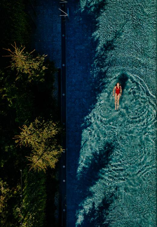 Frau schwimmt im Infinity Pool des Naturhotel Forsthofgut