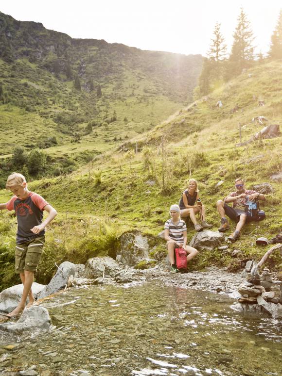 Familie wandert und macht Pause am Bergsee in Österreich Leogang