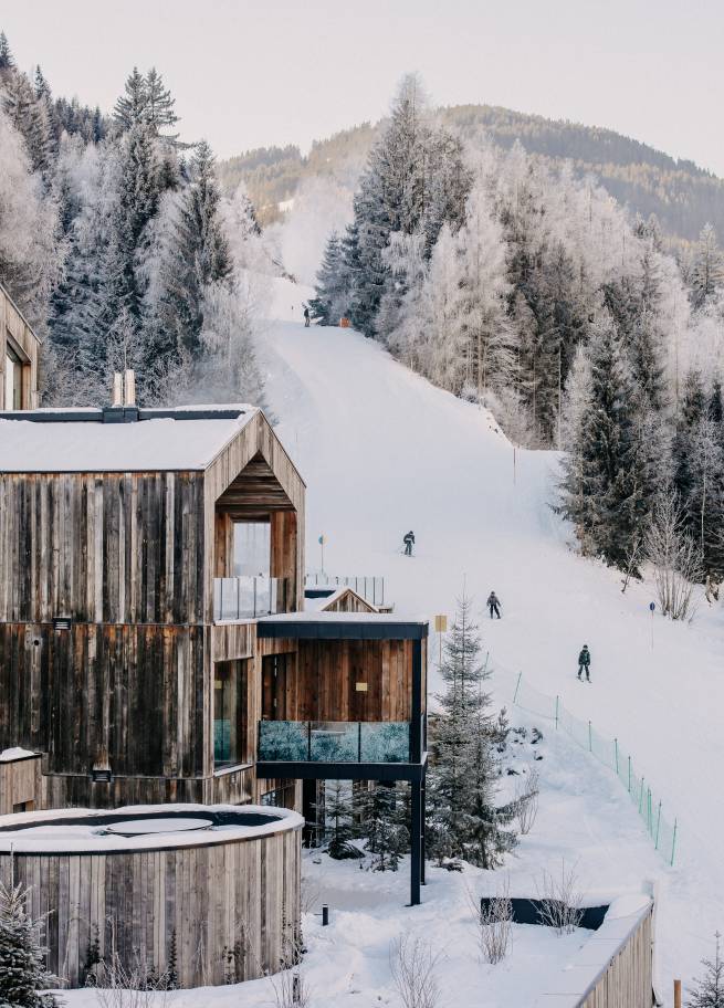 Außenansicht Naturhotel Forsthofgut im Winter mit Skifahrern