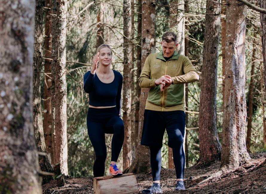 Fitness in Leogang - Personal Trainer mit Frau im Wald machen Sport