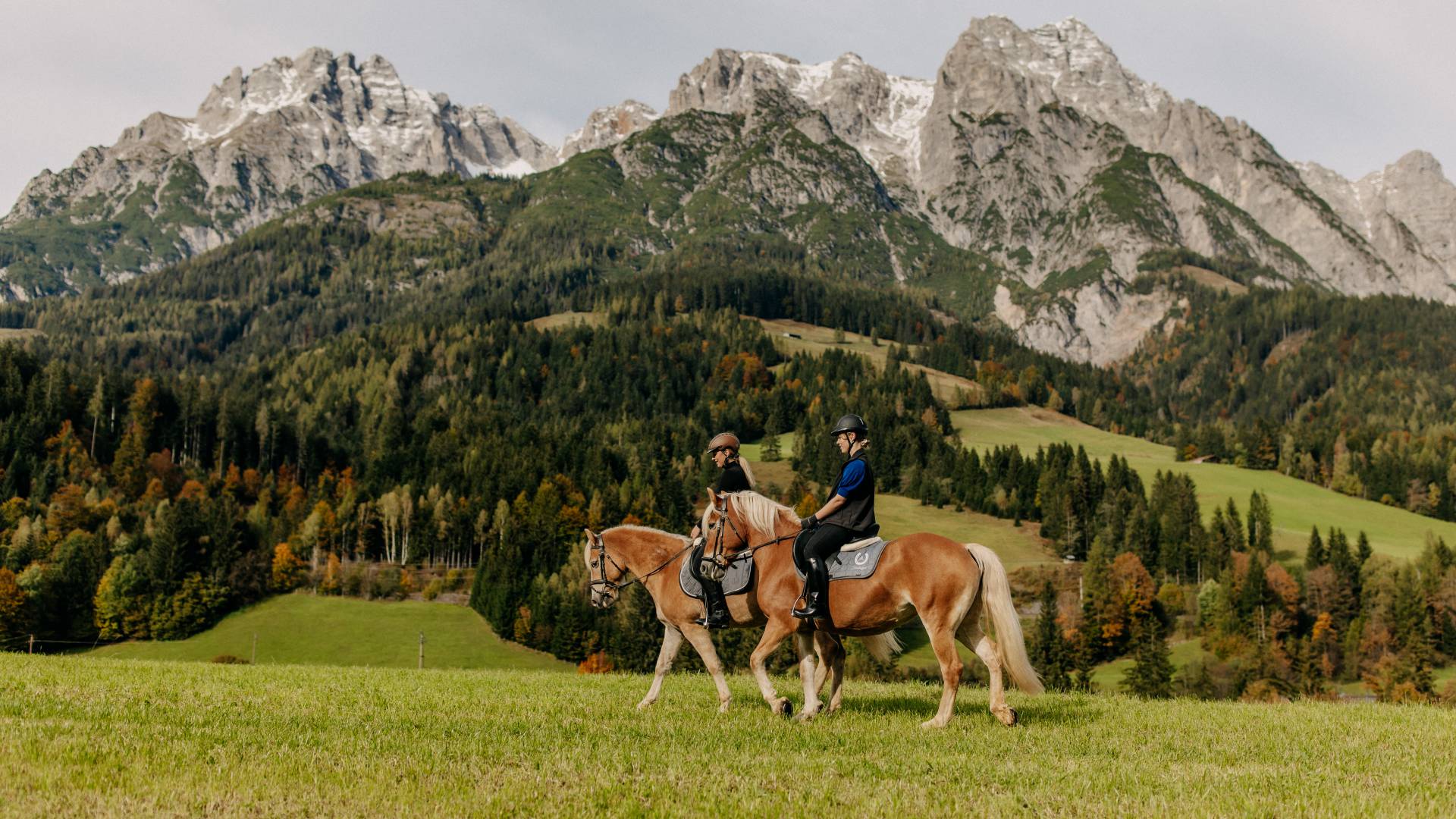 Zwei Reiter auf Haflingerpferden vor herbstlicher Bergkulisse in Leogang