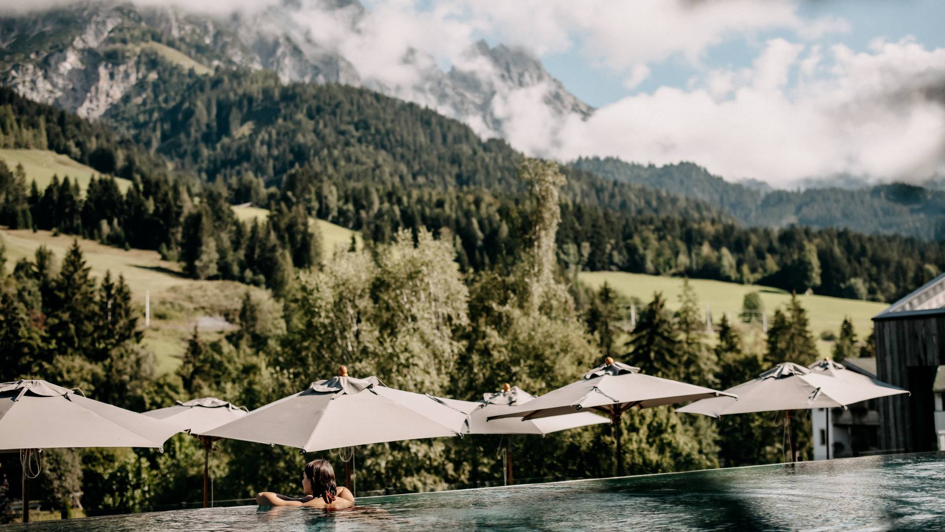 Woman in the infinity pool with a view of the Leoganger Steinberge mountains