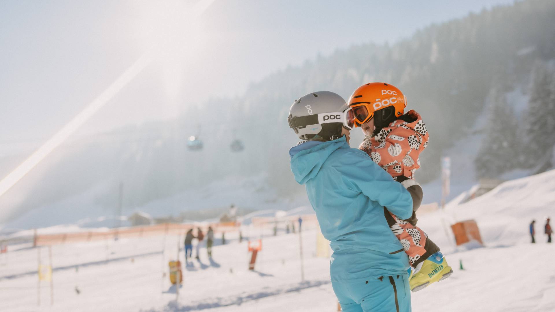 Person hält Kind auf den Armen im Skigebiet