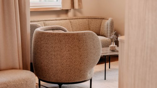 Nahaufnahme eines gemütlichen Sessels und einer Sitzecke mit Sofa und Beistelltisch.