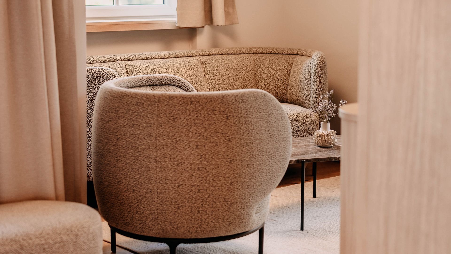 Close-up of a cozy armchair and a seating area with a sofa and side table.