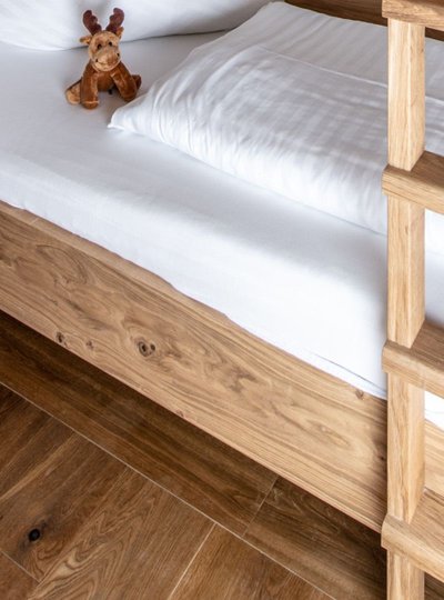 Section of a brightly furnished children's room with a bunk bed and a green cabinet. The mascot Rocky is sitting on the lower bunk.