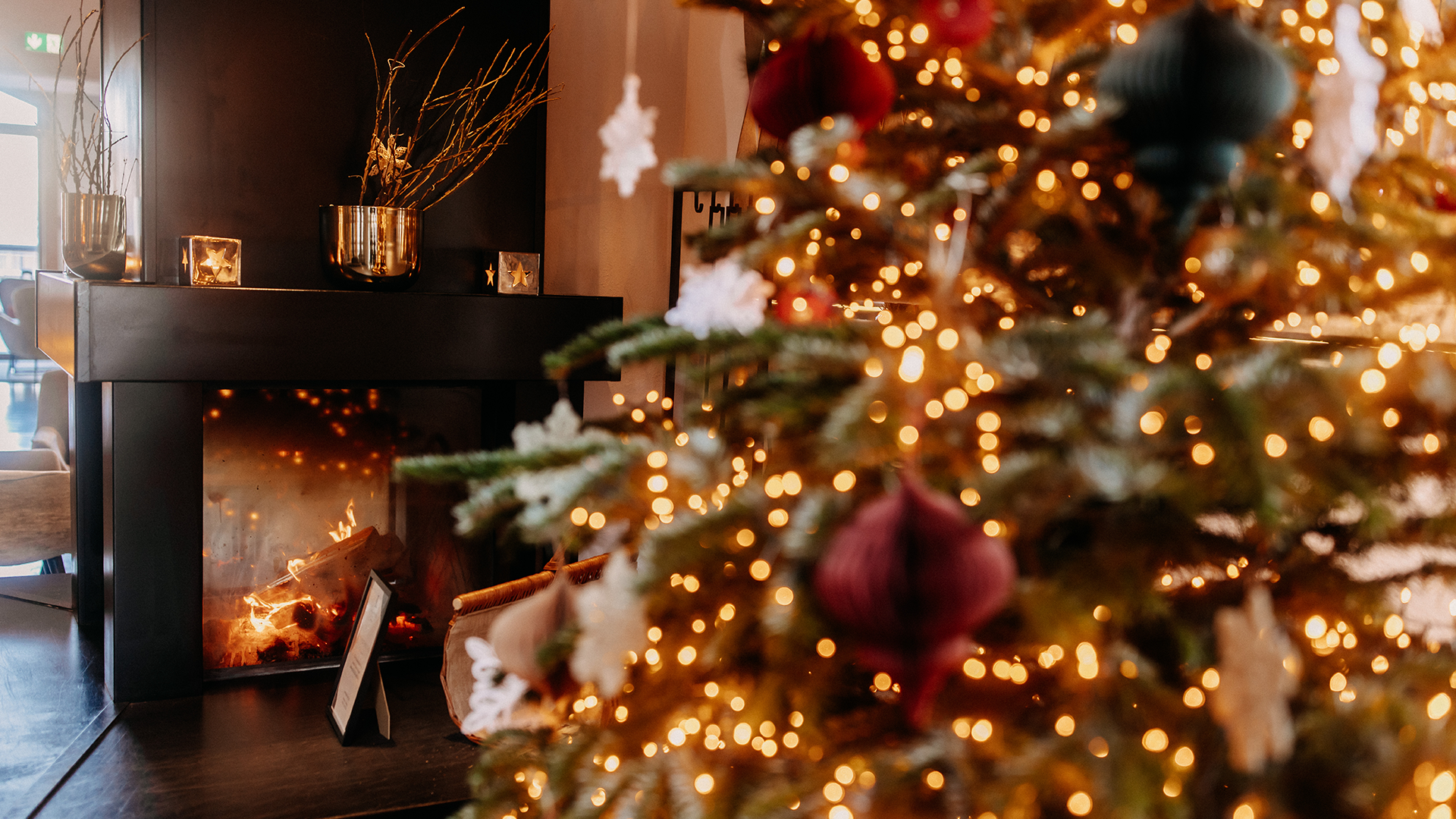 Festively decorated Christmas tree at Naturhotel Forsthofgut with a view of the fireplace in the background.
