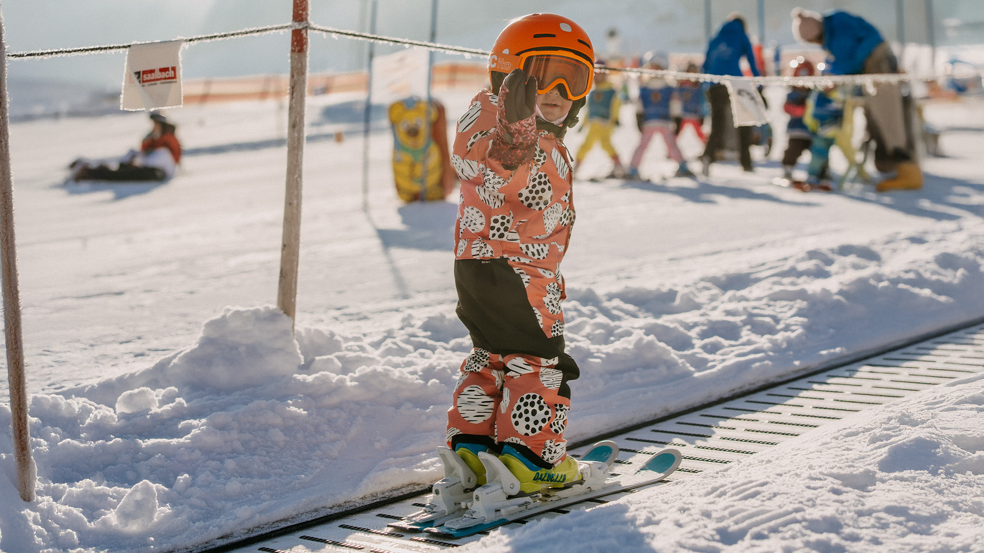 Ein Kind fährt im Kinderland auf dem Förderband im Schnee.