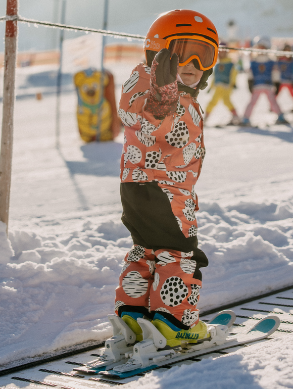 Ein Kind fährt im Kinderland auf dem Förderband im Schnee.