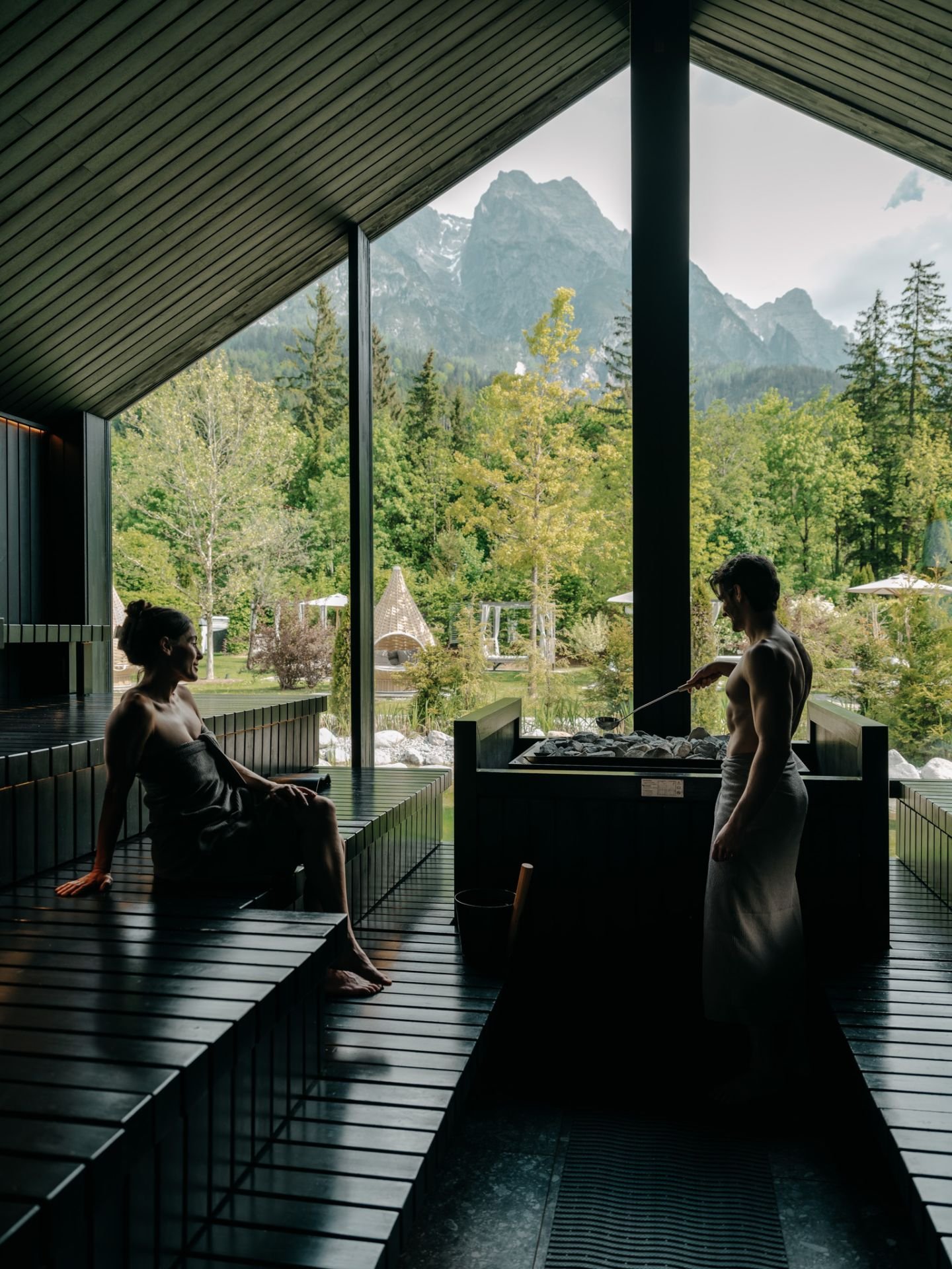 Paar beim Entspannen im Saunabereich des Naturhotel Forsthofgut in Leogang – exklusive Wellness-AusZEIT mit Blick in die Natur.