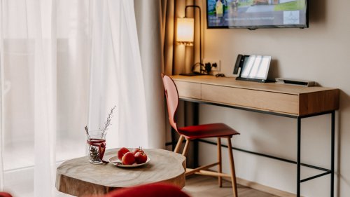 Decorated small table with a desk and an armchair behind it. Above the desk, a television is mounted on the wall.