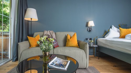 Naturzimmer Landidyll mit Sofa-Ecke, frischen Blumen und Zugang zum Balkon.