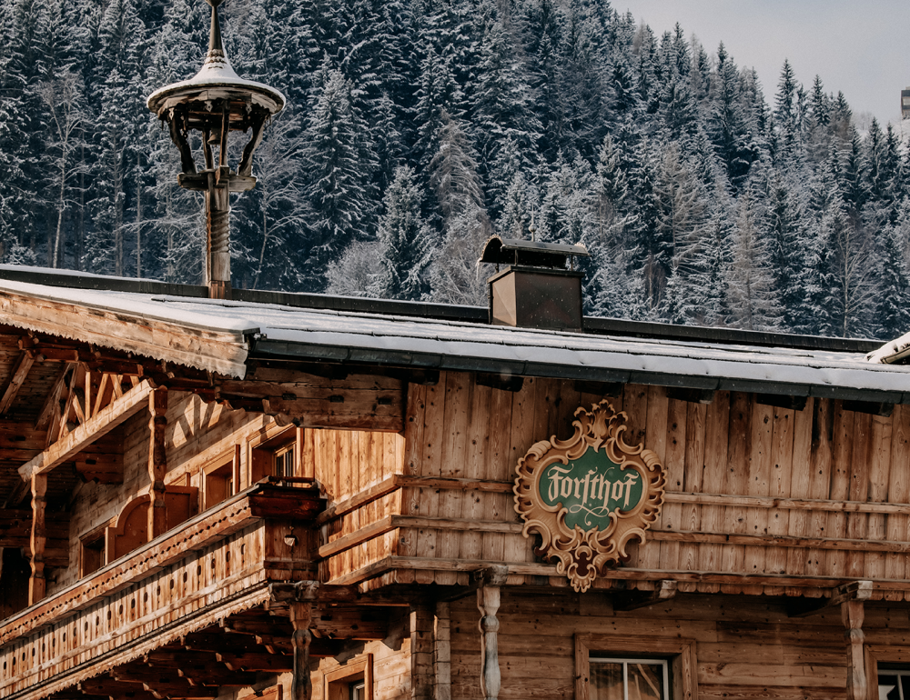Das Stammhaus des Naturhotels Forsthofgut im traditionellen Stil, eingebettet in die verschneite Alpenlandschaft.