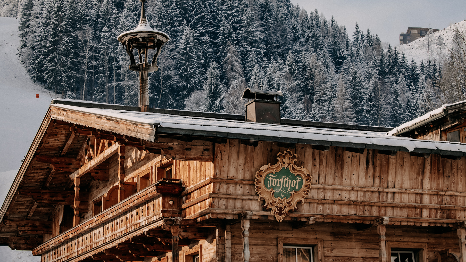 Das Stammhaus des Naturhotels Forsthofgut im traditionellen Stil, eingebettet in die verschneite Alpenlandschaft.
